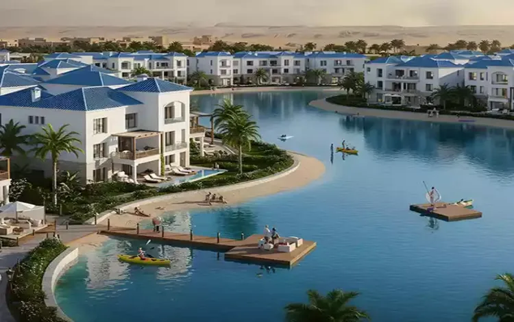 طلالة على بحيرات صناعية ومنازل فاخرة بواجهات بيضاء وأسقف زرقاء في مشروع جريان ماونتن فيو.